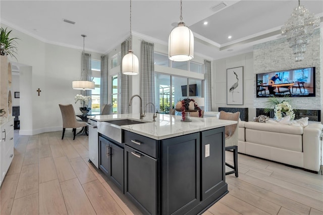 kitchen with crown molding, sink, pendant lighting, and a kitchen island with sink