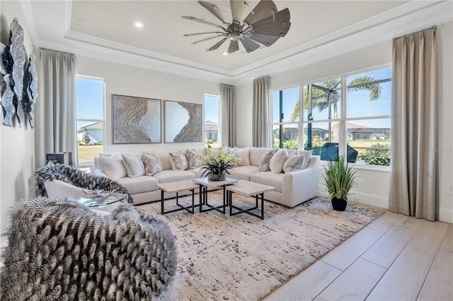 living room featuring ceiling fan, light hardwood / wood-style floors, ornamental molding, and a raised ceiling