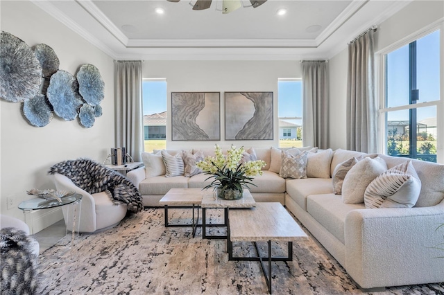 living room featuring ceiling fan, ornamental molding, a raised ceiling, and a healthy amount of sunlight