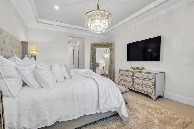 bedroom with hardwood / wood-style flooring, ornamental molding, a raised ceiling, and a notable chandelier