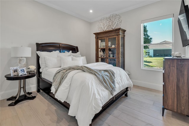 bedroom featuring light hardwood / wood-style floors, multiple windows, and crown molding