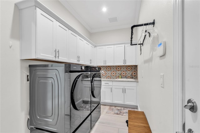 laundry area with sink, separate washer and dryer, ornamental molding, and cabinets