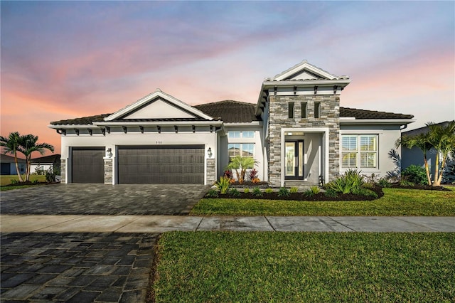 view of front of home with a garage and a lawn