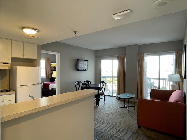 kitchen featuring white cabinetry, black electric stovetop, carpet flooring, white refrigerator, and sink