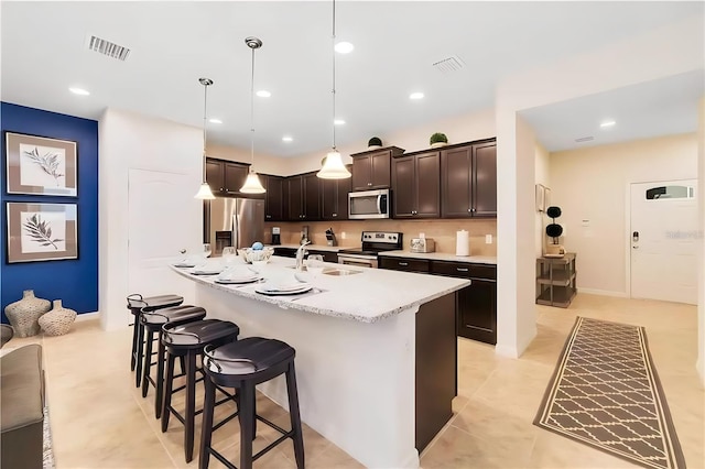 kitchen with sink, pendant lighting, a breakfast bar area, dark brown cabinets, and appliances with stainless steel finishes