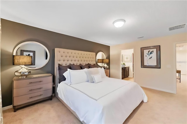 bedroom with light colored carpet and ensuite bath