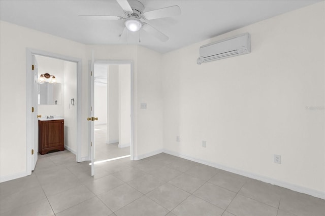 unfurnished bedroom featuring ensuite bathroom, sink, a wall mounted AC, light tile patterned floors, and ceiling fan