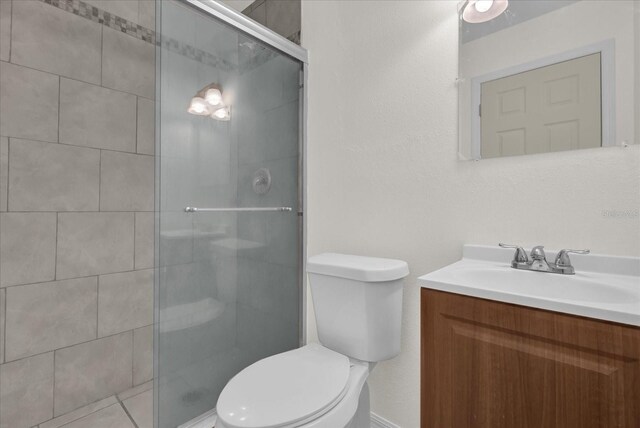 bathroom featuring vanity, toilet, and a shower with door