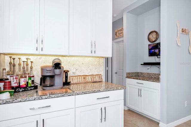 kitchen with white cabinets, decorative backsplash, light stone counters, and light tile patterned floors