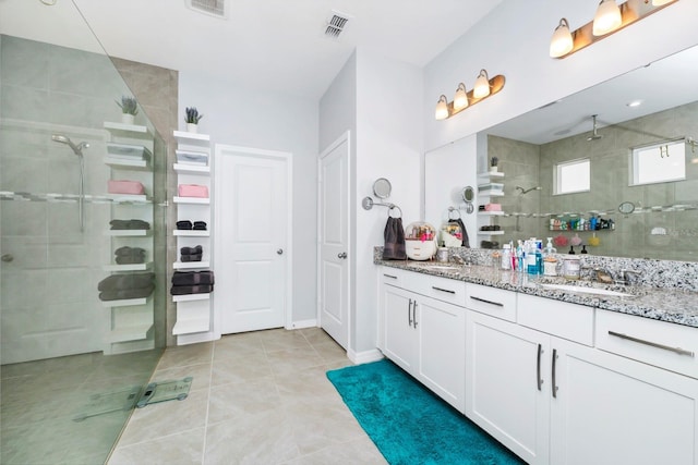 bathroom with tile patterned floors, vanity, and tiled shower