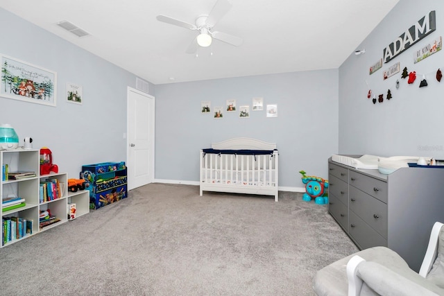 bedroom featuring a crib, light carpet, and ceiling fan