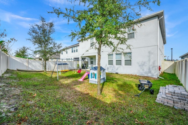 back of house featuring a yard and a playground