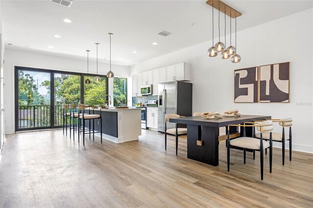 kitchen with pendant lighting, backsplash, white cabinets, a kitchen island, and stainless steel appliances