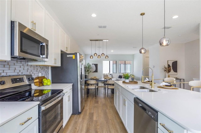 kitchen featuring white cabinets, decorative light fixtures, sink, and appliances with stainless steel finishes