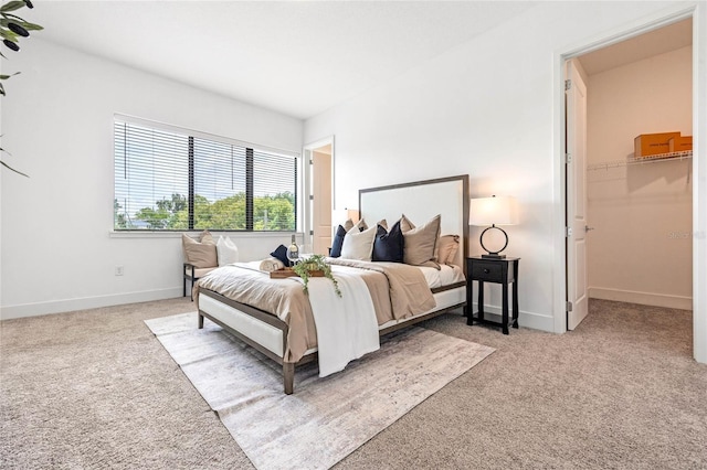 bedroom featuring light carpet and a walk in closet