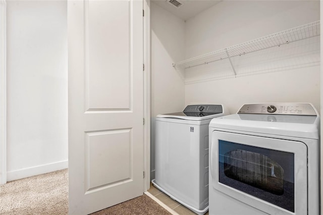 clothes washing area with washing machine and dryer and light carpet