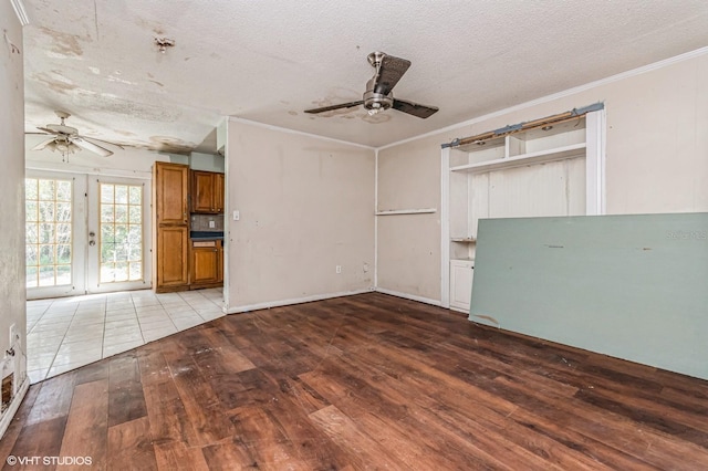 unfurnished living room with french doors, ornamental molding, ceiling fan, a textured ceiling, and hardwood / wood-style floors