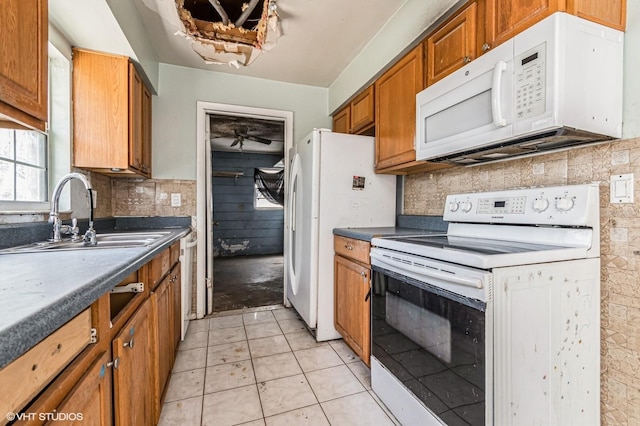 kitchen featuring white appliances, a sink, brown cabinets, tasteful backsplash, and dark countertops