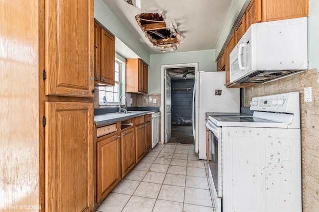 kitchen featuring white appliances, light tile patterned floors, brown cabinetry, a sink, and backsplash