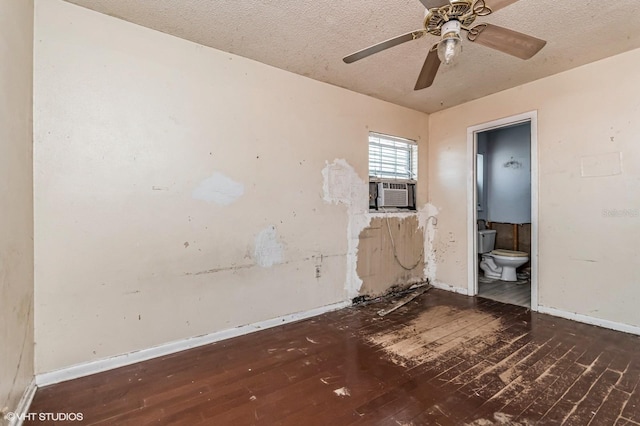 unfurnished room featuring cooling unit, a textured ceiling, baseboards, and hardwood / wood-style flooring