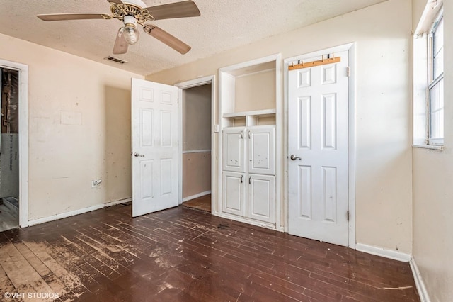 unfurnished bedroom with baseboards, visible vents, dark wood finished floors, and a textured ceiling