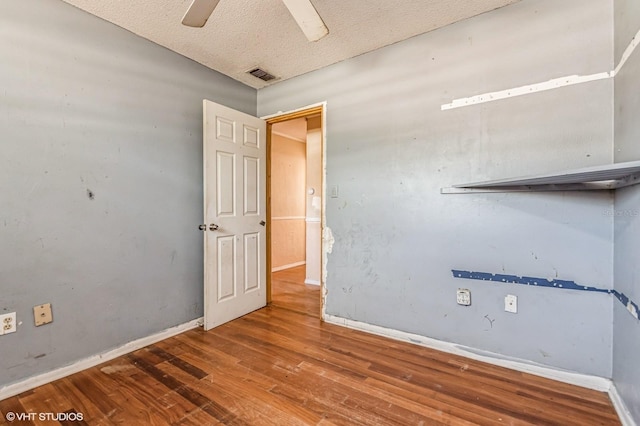 spare room featuring visible vents, ceiling fan, a textured ceiling, wood finished floors, and baseboards