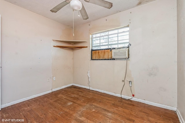 empty room featuring a textured ceiling, hardwood / wood-style floors, a ceiling fan, and baseboards