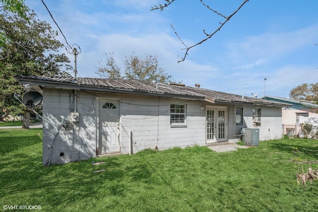 rear view of property with french doors, a yard, central AC unit, and metal roof