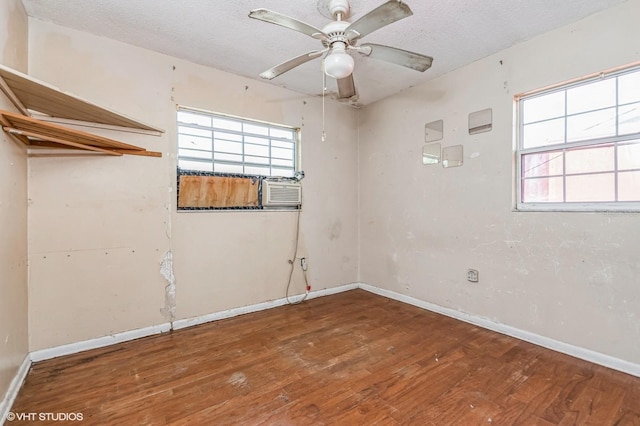 empty room with a healthy amount of sunlight, a textured ceiling, baseboards, and hardwood / wood-style flooring