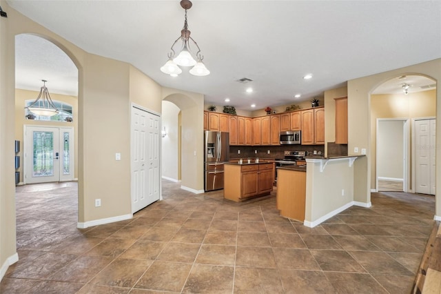 kitchen with tasteful backsplash, kitchen peninsula, a chandelier, pendant lighting, and appliances with stainless steel finishes