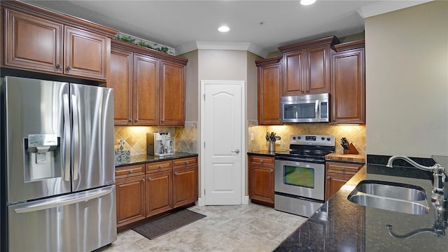 kitchen featuring sink, stainless steel appliances, dark stone countertops, crown molding, and decorative backsplash