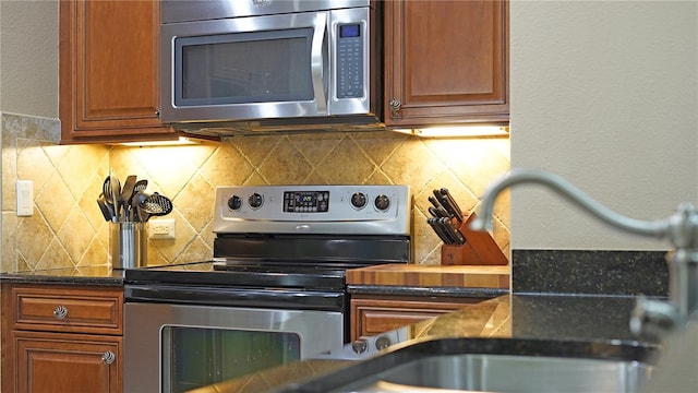 kitchen with dark stone counters, sink, appliances with stainless steel finishes, and tasteful backsplash