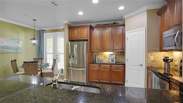 kitchen featuring pendant lighting, sink, dark stone countertops, ornamental molding, and appliances with stainless steel finishes