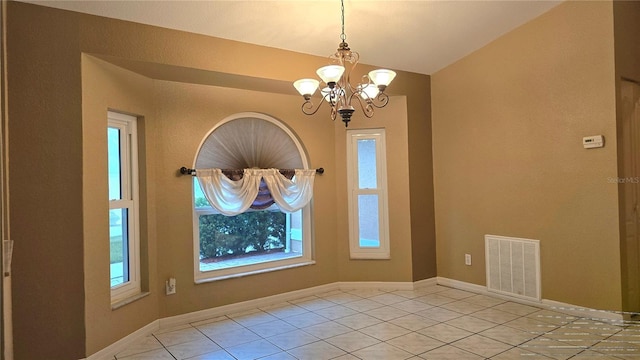 empty room with a notable chandelier and light tile patterned flooring