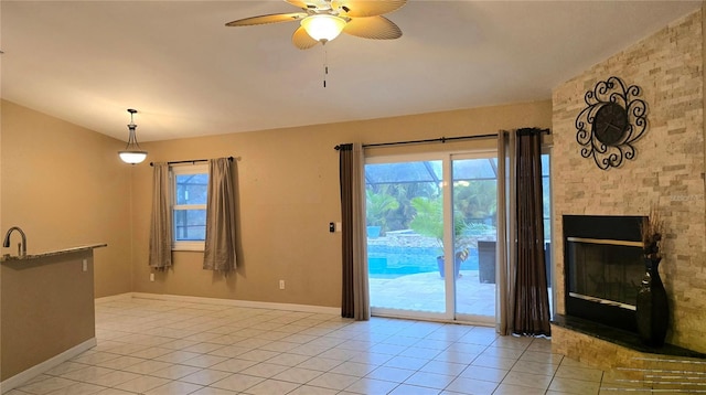 interior space with ceiling fan, light tile patterned floors, a fireplace, and vaulted ceiling