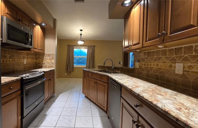 kitchen with backsplash, light stone countertops, sink, and stainless steel appliances