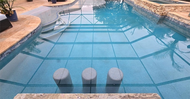 view of swimming pool with an in ground hot tub