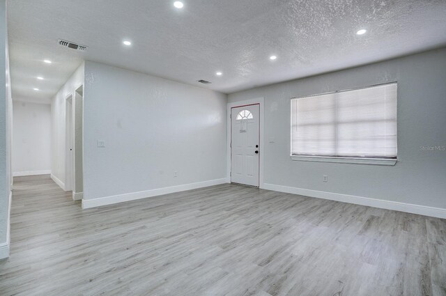 entrance foyer with light hardwood / wood-style floors and a textured ceiling