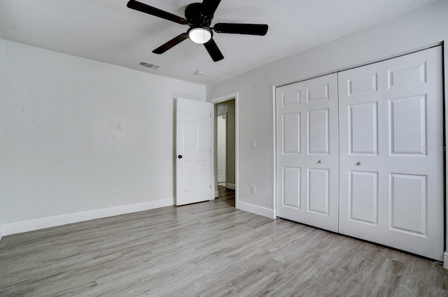 unfurnished bedroom featuring ceiling fan, light hardwood / wood-style floors, and a closet