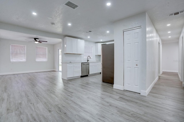 kitchen featuring white cabinetry, sink, a textured ceiling, appliances with stainless steel finishes, and light wood-type flooring