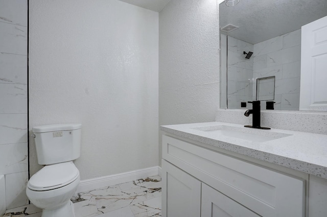 bathroom with a textured ceiling, vanity, toilet, and tiled shower