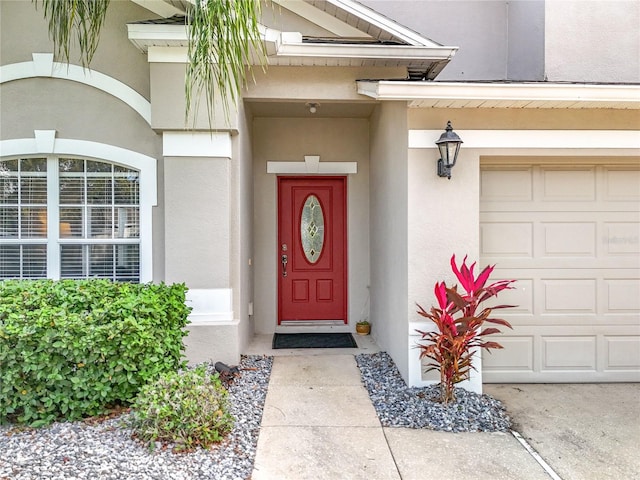 doorway to property with stucco siding and a garage