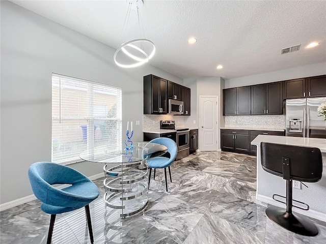 kitchen with appliances with stainless steel finishes, tasteful backsplash, and dark brown cabinets