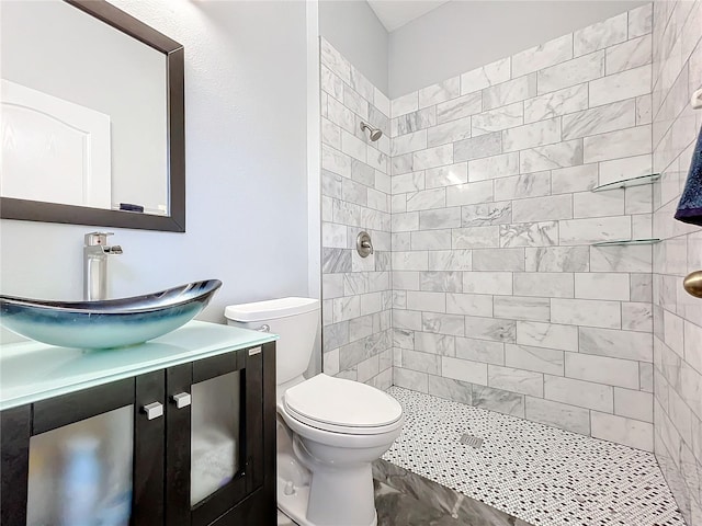 bathroom with a tile shower, vanity, and toilet