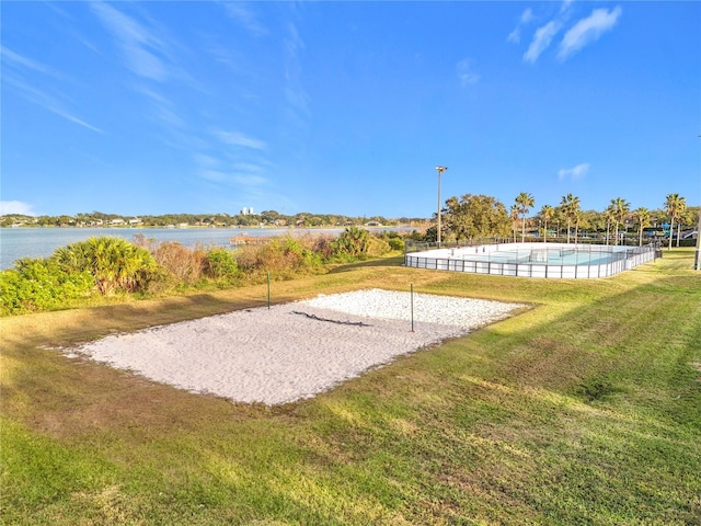 view of property's community with volleyball court, a yard, and a water view