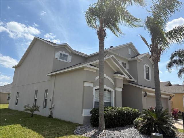 view of home's exterior with stucco siding, a yard, and a garage