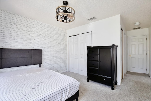 bedroom featuring brick wall, light colored carpet, a textured ceiling, and a closet