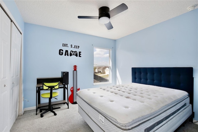 carpeted bedroom with ceiling fan, a closet, and a textured ceiling