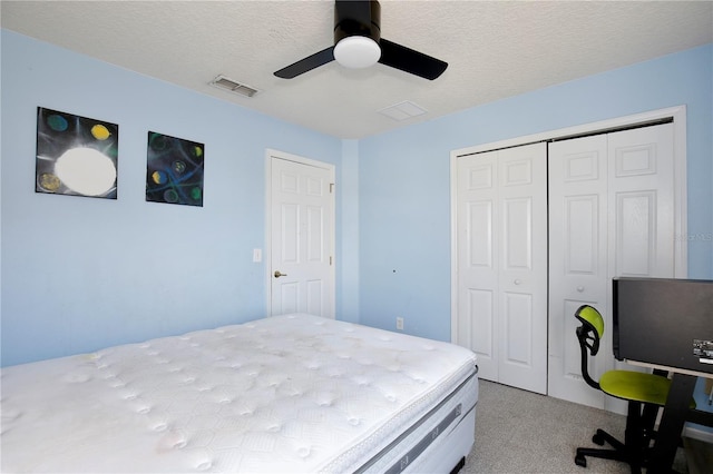 bedroom featuring ceiling fan, light carpet, a textured ceiling, and a closet