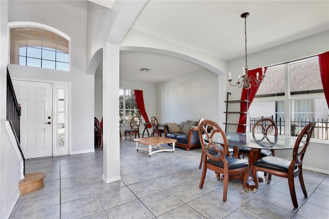 tiled dining area featuring a textured ceiling and a chandelier